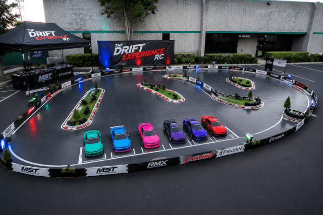 The full Drift Experience RC track set up in a parking lot with sponsor banners and the RC drift car fleet staged at the start
